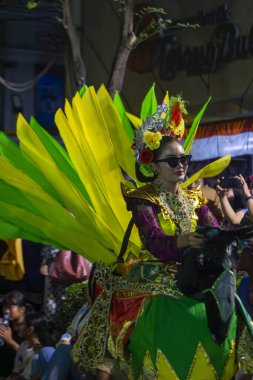 Yogyakarta, Endonezya-6 Ağustos 2025: Coşkulu bir seyircinin katıldığı canlı bir sokak geçidi sırasında canlı, geleneksel kostümlü bir sanatçının katıldığı festival etkinliği.