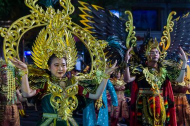 Yogyakarta, Endonezya-6 Ağustos 2025: Gösterişli bir kültürel geçit töreni sanatçıları özenle hazırlanmış geleneksel kostümler içinde, altın elementlerin yer aldığı, izleyicileri büyüleyen ve bir gece arkaplanı ve gelenekleri kutlayan.