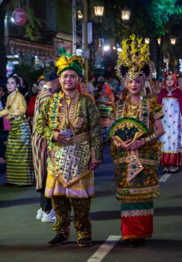 Yogyakarta, Endonezya-6 Ağustos 2025: Özenle hazırlanmış geleneksel giysiler sergileyen iki kişi, canlı bir atmosfer ve canlı dekorasyonlarla, bölgesel kutlama ve kültür mirasının somutlaştırılmış olduğu festivalsel bir kültür sokak geçidine katılıyor.