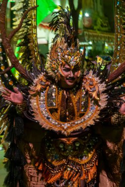 Yogyakarta, Endonezya-6 Ağustos 2025: Gece şenliği sırasında canlı giyinen, ayrıntılı zanaatkarlık, canlı renkler ve kültürel kutlamaların vurgulandığı, karmaşık bir kültürel kostüm sergileyen sanatçı.