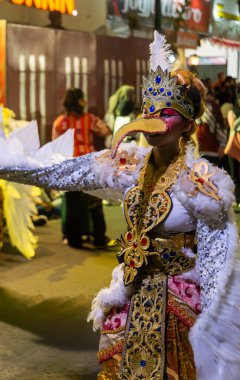 Yogyakarta, Endonezya-6 Ağustos 2025: Özenle hazırlanmış bir kostüm içindeki parlak giyimli bir birey, büyüleyici bir sokak festivali sırasında kültür geleneklerini ön plana çıkarıyor, cazibe, zarafet, sanat ve yerel mirasın güzelliğini ilgi çekici bir sahnede sergiliyor..