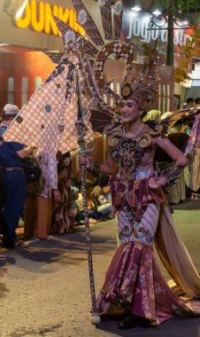 Yogyakarta, Endonezya-6 Ağustos 2025: Canlı şehir dekorasyonları ve coşkulu izleyicilerle çevrili, özenle hazırlanmış bir kültür geçidi sırasında eşsiz geleneksel bir kostüm içindeki bir kişinin canlı bir şekilde sergilendiği bir kutlama.