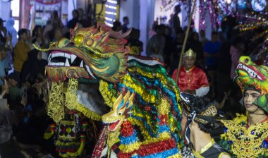 Yogyakarta, Endonezya-6 Ağustos 2025: Detaylı ejderha kostümleri, renkli dekorasyonlar ve geleneksel sokak geçit töreninde geleneksel mirası kutlayan coşkulu katılımcılar.