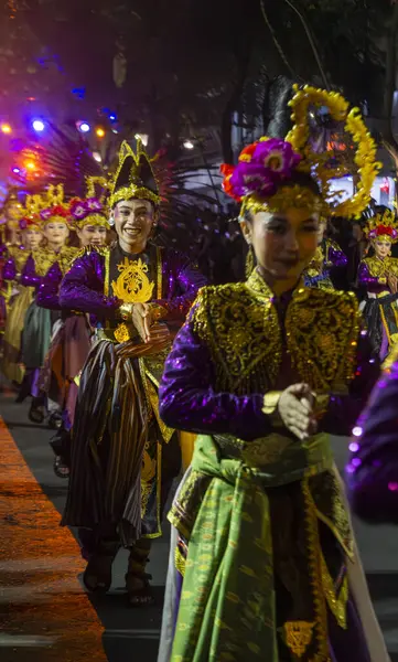 Yogyakarta, Endonezya-6 Ağustos 2025: Büyüleyici bir gece kültürel kutlaması sırasında gösterişli giyinmiş sanatçılar, neşeli ışıklar ve canlı renklerle çevrelenmiş, neşe dolu ifadeler sergiliyorlar. 