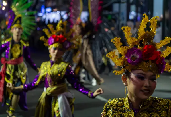 Yogyakarta, Endonezya-6 Ağustos 2025: Canlı bir caddedeki kültürel geçit törenine katılan renkli kostümler ve ayrıntılı başlıklar giymiş dansçıların festival sahnesi.