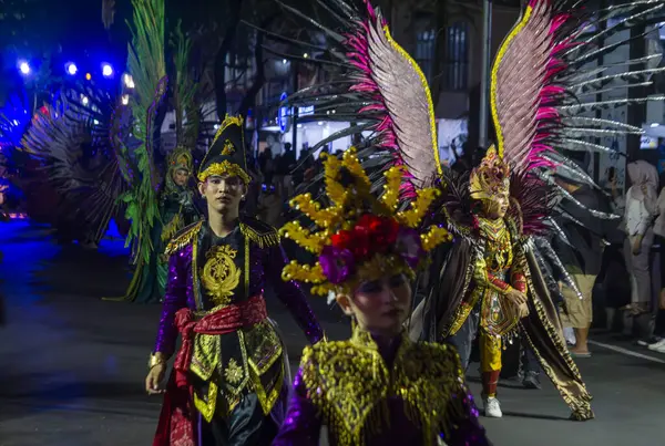 Yogyakarta, Endonezya-6 Ağustos 2025: Bir gece etkinliği sırasında canlı renklerin ve karmaşık tasarımların yer aldığı, kültürel mirasın sergilendiği ve şenlikli atmosferin yer aldığı geleneksel kostümlerin giyildiği canlı bir geçit töreni sahnesi.