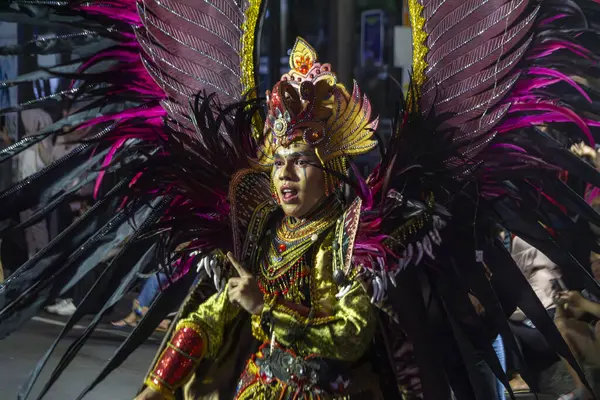 Yogyakarta, Endonezya-6 Ağustos 2025: Hareketli bir sanatçı, coşkulu bir kutlamayla aydınlık kültür sanatını gözler önüne seren, siyah ve pembe kanatların yer aldığı, karmaşık detayların yer aldığı özenle hazırlanmış bir kıyafetle seyirciyi büyülüyor 