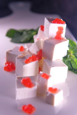 Kırmızı havyarla süslenmiş kırmızı havyarlı FetaFeta peyniri beyaz tabakta otlarla süslenmiş kırmızı havyarla süslenmiş beyaz tabakta. Yüksek kalite fotoğraf. Restorandaki yemek çok lezzetli.