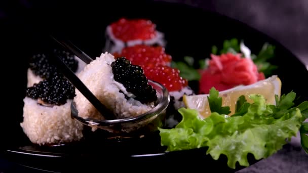 Sticks Take Sushi Restaurant Lights Background 种类繁多的寿司与红色鱼子酱 费城奶酪和筷子特写 一套美味的日本寿司滚在石板上 — 图库视频影像