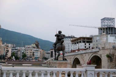 Makedonya 'nın kuzeyindeki Üsküp kentinde seyahat yürüyüşleri yapan müzelerin merkezindeki binalar görülüyor. Vardar Nehri çevresindeki yeni ve tarihi binalar