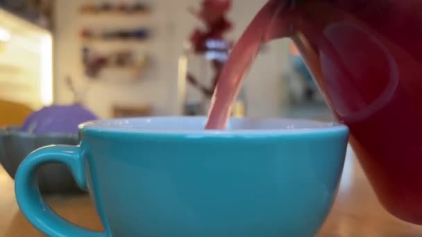 Gießen Himbeertee Aus Einer Glasteekanne Eine Blaue Tasse Nahaufnahme Eines — Stockvideo