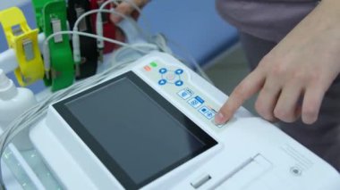 Bir kardiyolog hastaya kardiyogram yapar. Profesyonel doktorun kadın elleri modern klinikteki hasta adamı daha detaylı incelemek için kardiyogramı tutar. Tıptaki son teknolojiler. 