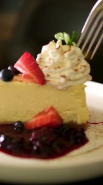 Cheesecake 'ten bir ısırık alıyorum. Klasik New York peynirli kek dilimi, çatalla yemek. New York peynirli keki, yaban mersini kremalı ve buruşuk çatallı lezzetli bir tatlı.