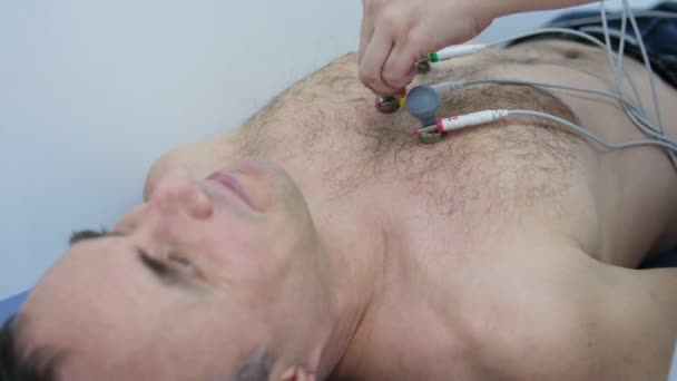 用毛茸茸的胸腔把吸盘贴在胸腔上的男人做心动图的问题不可能消失 这使得心动图进行测试的技术装置不方便 高质量的 — 图库视频影像