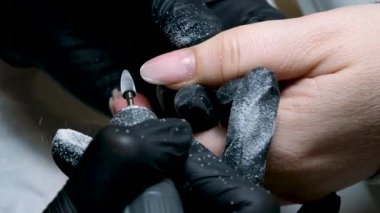 Manikür keskisi kullanarak tırnakları temizliyorum. Makro. Yakın plan jel, manikür makinesi, kadın usta. Manikürcü kuaförde tırnak makası ile oje temizliyor, manikürcü dosyası müşterileri çiviliyor. 