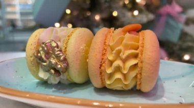 Fındık aromalı kayısı tatları Noel ağacının arka planında. Yeni yıl tatlıları, tabakta iki badem kurabiyesi, kamera, yaldızlı cevizi ve yenilebilir altını filme çekiyor..