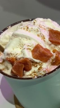 Balkabağı aromalı, köpüklü ve kremalı balkabağı. Demir bardaktaki latte krema parçalarını karıştırmak için altın bir kaşık kullanılıyor. Kakao gibi görünüyor..