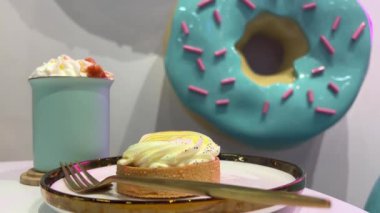 Pembe süslemeli kocaman mavi donutun arka planında içki ve tart olan bir kafe. Yüksek kaliteli FullHD görüntüler