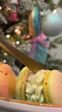 Yılbaşı gecesi Noel ağacının arka planında yetişkin ve yaşlı bir kadının eli bir kafede lezzetli bir kurabiye içeceği kesiyor. Kremalı latte soslu büyük köpük. 