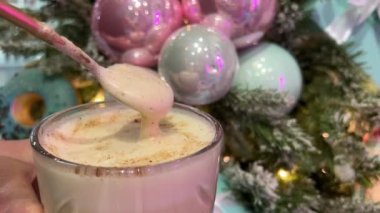 Pembe ve mavi Noel ağacı süslemelerine karşı cam bardakta çikolatalı cappuccino latte sütlü kakao. Kadın elleri kaynatır, yaşlı kadın içkisini hazırlar.