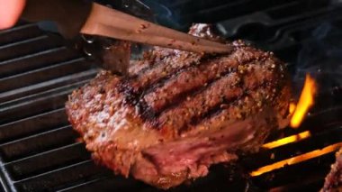 Ateşli, sulu, pişmiş et dilimlerinin yakından görüntüsü. Orijinal yemek tarifi. Profesyonel aşçılık, yemek tarifi, yemek pişirme. Ateşin üstünde biftek pişirirken çekilmiş kaliteli bir video.
