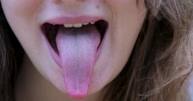 Pembe dilini çıkar. Kadın içki lekeli dilini gösteriyor. Yakın çekim, ön manzara, yüz, tanınmaz halde. Yüksek kalite 