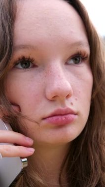 Yüzündeki beyaz telefon, gölcüklü gülüşün arka planına karşıydı. Saniyede 60 kare konuşuyordu. Parkta durup cep telefonuyla sohbet eden mutlu bir kızdı. Yüksek kalite 