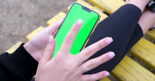 在公园里玩智能手机的孩子 在智能手机上浏览互联网的孩子 在设备上打字的金发少女 漂亮的白人女孩在户外用手机发短信 — 图库视频影像