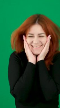 Krom anahtar stüdyo duygularında yeşil arka planda olan kızıl saçlı genç bir kadın. Kahverengi gözlü, açık tenli, Avrupalı Amerikalı. Zıplayan kadın mutluluğun sevinciyle seviniyor. Elleriyle kendini tutuyor.