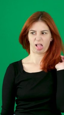 dikey video. Krom anahtar stüdyo duygularında yeşil arka planda olan kızıl saçlı genç bir kadın. Kahverengi gözlü, açık tenli, Avrupalı Amerikalı. Kanada. 