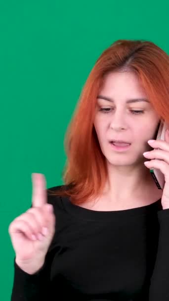 在电话里讲红头发女孩的垂直视频 红头发的年轻女性 背景是绿色的 有着深褐色的关键演播室情感 近视棕色的眼睛 浅色的欧洲裔美国人 加拿大 — 图库视频影像