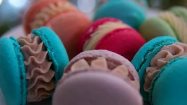 Badem unundan yapılmış kırmızı, mavi, turuncu, pembe ve turuncu Fransız hamur işlerinde kremalı, iştah açıcı yami yami. bir Noel ağacının arka planında