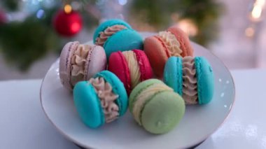 Badem unundan yapılmış kırmızı, mavi, turuncu, pembe ve turuncu Fransız hamur işlerinde kremalı, iştah açıcı yami yami. bir Noel ağacının arka planında