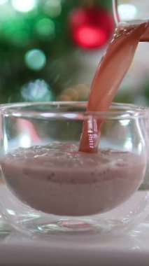 Sütsüz süt ineği sütü. Muzlu muz püresi cam bardağa doluyor. Lezzetli bir ikram. Yeni yıl arifesi için kakao ve krema ekle.