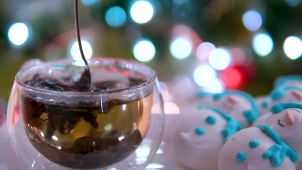 在圣诞树的背景下倒入热茶 在盘子里放上美味的甜食 制成雪人蛋白糖霜 使白糖绿茶杯蒸汽热饮温暖舒适 圣诞节 — 图库视频影像
