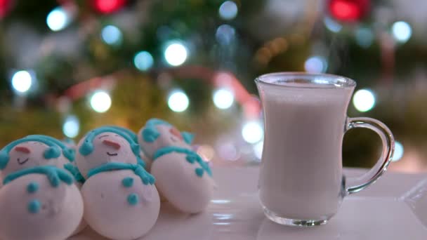 圣诞树旁的一杯热牛奶白盘上的雪人美味的零食晚餐花些时间庆祝圣诞健康食品彩色灯泡 高质量的 — 图库视频影像
