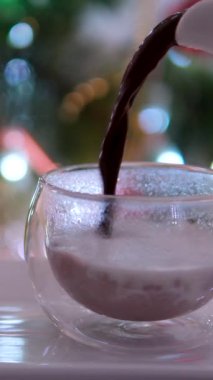 Bir kadın eli sıcak kakaoyu cam bardağa doldurur ve şekerleme ekler. Çikolata ve vanilya aromalı nefis bir içecek. Ağır çekim. Yüksek kalite 