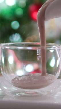 Sütsüz süt ineği sütü. Muzlu muz püresi cam bardağa doluyor. Lezzetli bir ikram. Yeni yıl arifesi için kakao ve krema ekle.