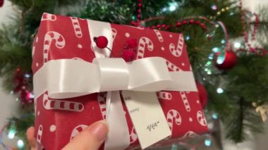 Hediye Noel ağacının altında yatıyor. Noel ağacının yanında yeni yıl hediyelerini paketlemek güzel hediyeler kırmızı paketlerle süslenip sevilen bir zanaatkar için Noel hediyesi olarak farklı süslemeler yapmak.