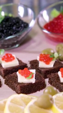 Siyah arka planda birbirine benzeyen iki cam kasede kırmızı ve siyah havyar. Erkek kaşığı havyar. Yüksek kalitede servis edilen havyar farklı türlerde havyar tatma zenginliği katıyor.