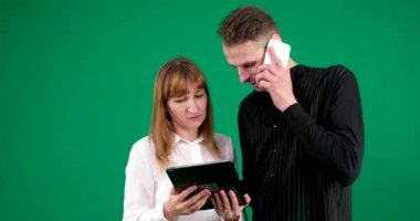 Elinde tablet telefonu olan erkek ve kadın ellerinde yeşil arka planda konuşan kahkahalar toplantıda internet flörtleşen ilişkiler üzerine çalışmayı öğreniyorlar. Çift çözme sorunu