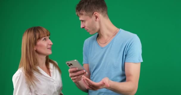 男人和女人手握电话 争论不休 拿定主意 妥协摇头 消极地不满在家里的首要问题是一对年轻人的绿色背景夫妇 — 图库视频影像