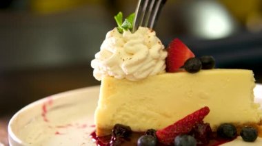 Loş ahşap masa temeli üzerinde servis edilen çilekli cheesecake. Video animasyonu. Yüksek kalite 4k görüntü