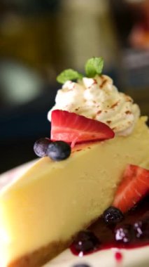 Loş ahşap masa temeli üzerinde servis edilen çilekli cheesecake. Video animasyonu. Yüksek kalite 4k görüntü