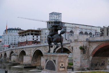 Makedonya 'nın kuzeyindeki Üsküp kentinde seyahat yürüyüşleri yapan müzelerin merkezindeki binalar görülüyor. Vardar Nehri çevresindeki yeni ve tarihi binalar