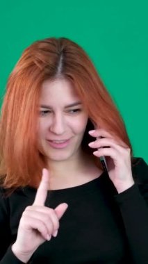 dikey video. Krom anahtar stüdyo duygularında yeşil arka planda olan kızıl saçlı genç bir kadın. Kahverengi gözlü, açık tenli, Avrupalı Amerikalı. Kanada. 