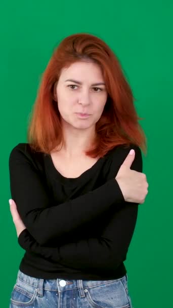 垂直录像 红头发的年轻女子在绿色的背景下 在一个彩色的关键工作室情感紧密棕色的眼睛浅色的皮肤 伤心哭泣的女人拥抱着自己 — 图库视频影像