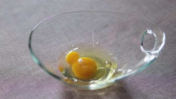 クッキング 生の鶏卵は殴られる前にスパイスで味付けされます 割れた卵が白いセラミックボウルに落ちる 卵を割るためのスローモーションビデオ 高品質の4K映像 — ストック動画