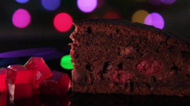 Klasik çikolatalı kek, beyaz tabanlı. Kirazlı çikolatalı kek ve parlak şehir ışıklarının koyu arka planında meyve jölesi.
