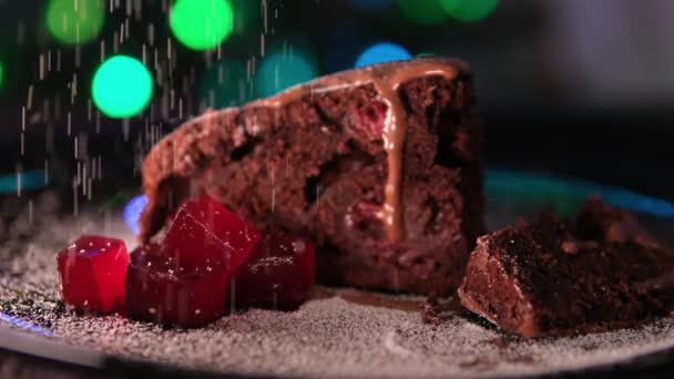 在城市灯火或圣诞树灯火的背景下 将糖粉巧克力巧克力布朗尼蛋糕洒在有樱桃果冻片的盘子里 作为新年甜点 高质量的 — 图库视频影像
